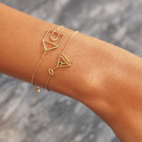 Gold chain bracelet with martini drink shaped pendant and small emerald worn by woman