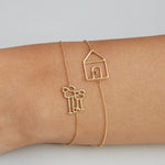 Gold chain bracelets with family and house shaped gold pendants on model's wrist
