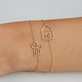 Gold chain bracelets with family and house shaped gold pendants on model's wrist