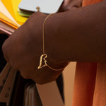 Gold chain bracelet with dinosaur shaped pendant worn by model