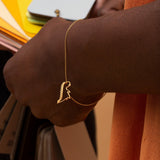 Gold chain bracelet with dinosaur shaped pendant worn by model