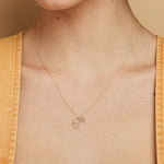 Gold chain necklace with small croissant shaped pendant worn by model