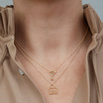 Gold chain necklace with martini drink shaped pendant and small emerald worn by model