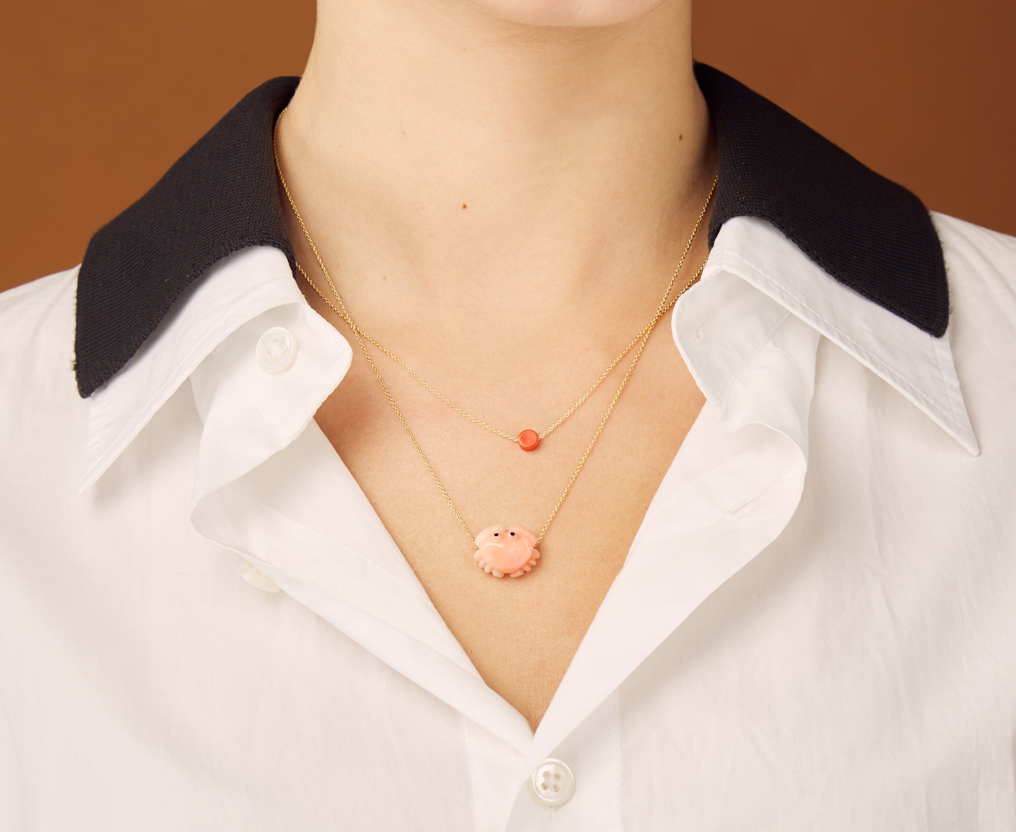 Gold chain necklace with sun shaped coral pendant worn by model